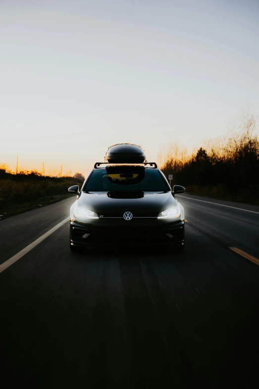 an automobile is driving down the road with a surf board on top