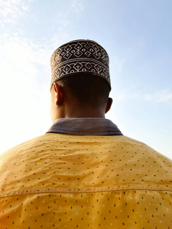 man in yellow shirt wearing a large colorful head wrap