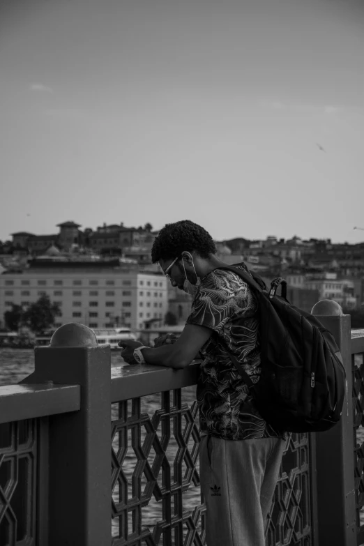 a woman on a bridge looking down at her cell phone