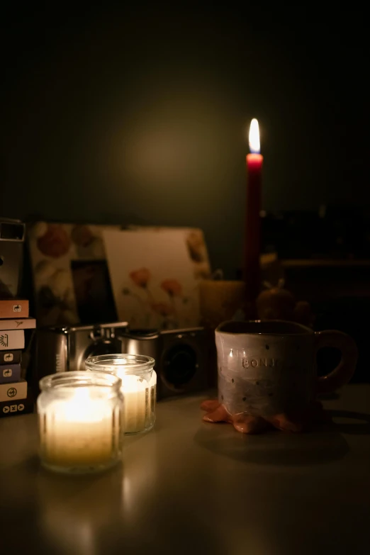 a lighted candle sits on a table beside books