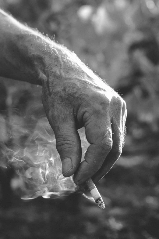 a man holding a cigarette in the air with smoke in his hand