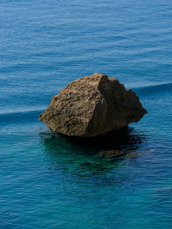 a small boat is out in the water near a rock