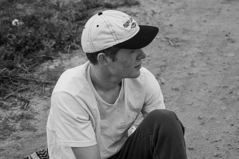 a man sitting on a dirt road in the middle of the day