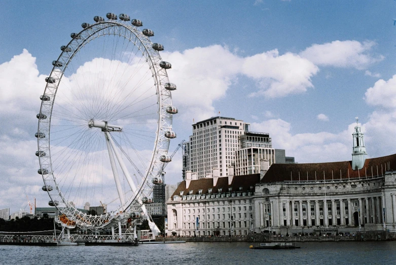 a large ferris wheel next to a building and some water