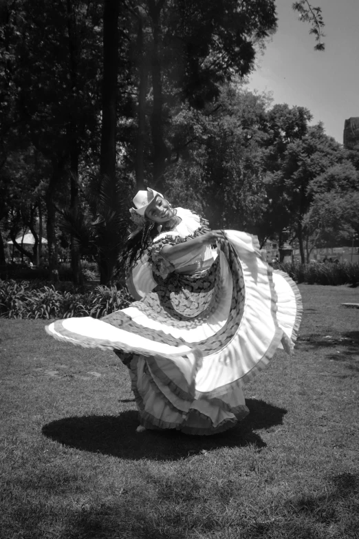 a woman in a dress is dancing in the park