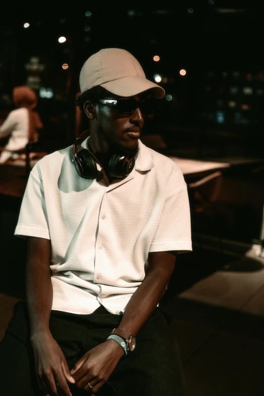 a man wearing a hat sitting on a chair with headphones