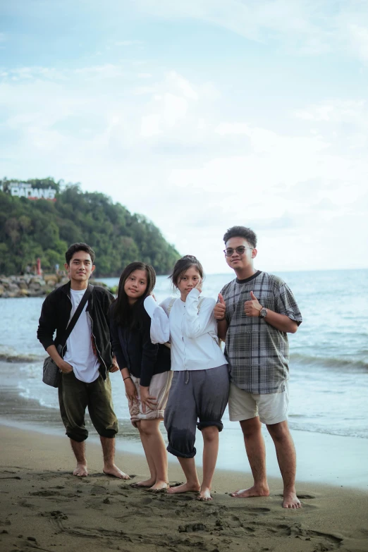 four people standing on a beach next to the ocean