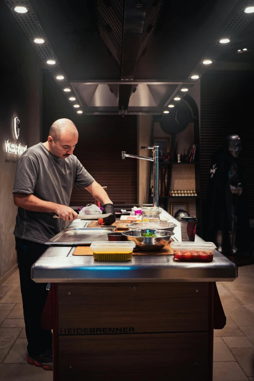 the man is preparing a dish in the dark kitchen