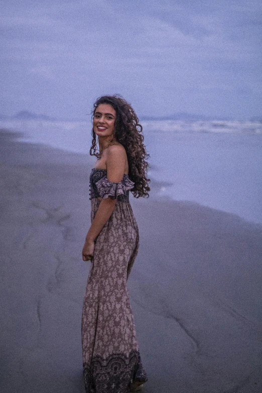 a woman standing on a beach with a blue sky