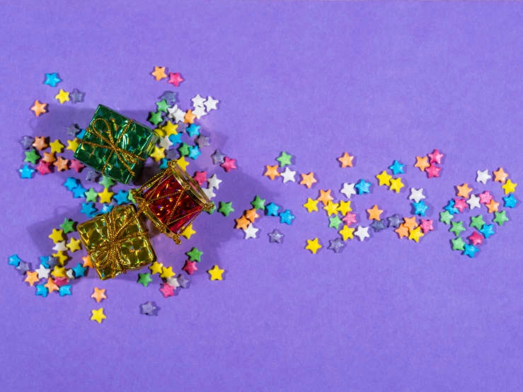 a little gift box sits next to a lot of stars on a purple background