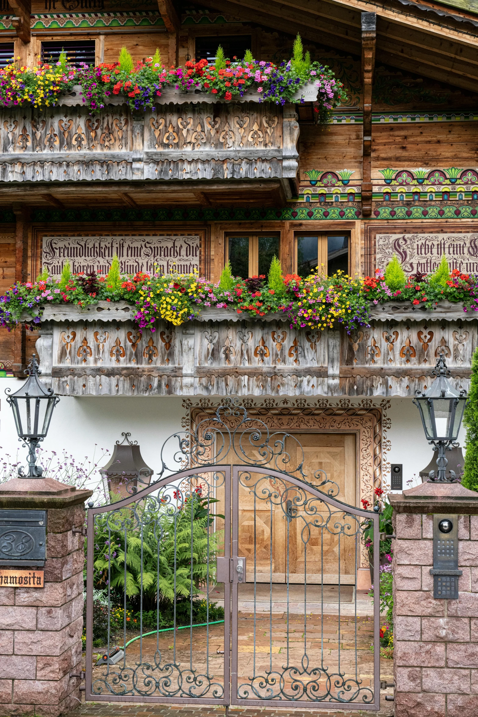 a stone and wooden house has two wrought iron gates