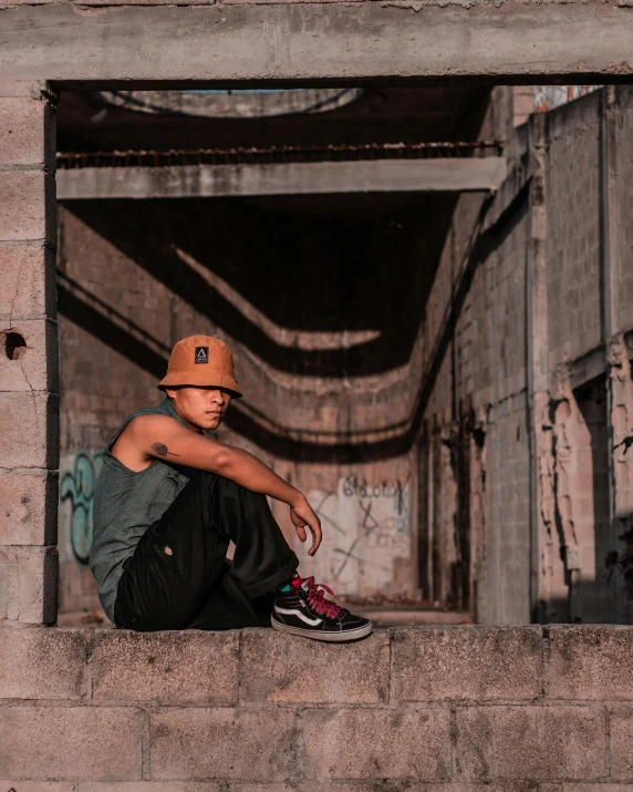 a young man sitting on a wall under a bridge
