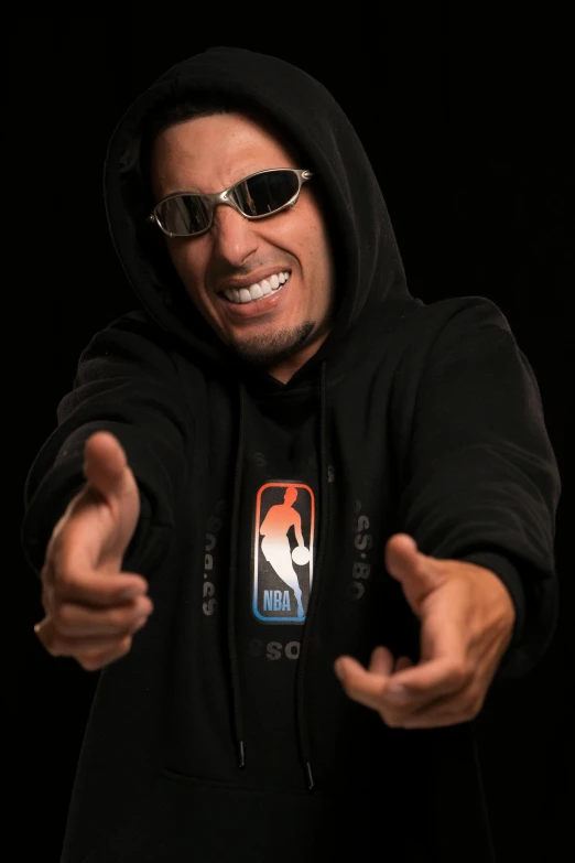 man in black sweatshirt with hoodie holding a glass pointing