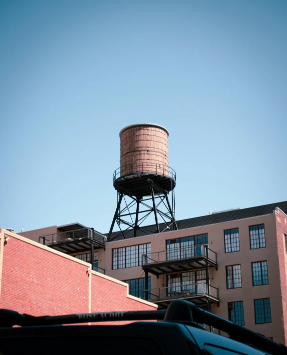 the top of a water tower sits above an old brick building