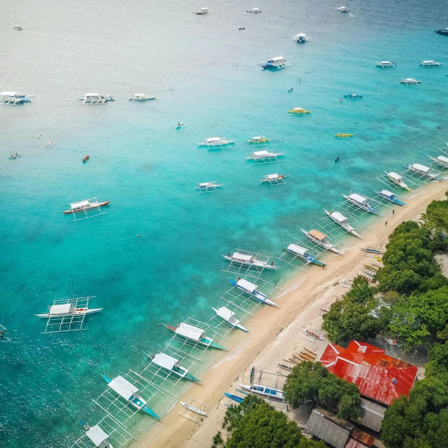 several small boats in the water, with a sandy beach behind them