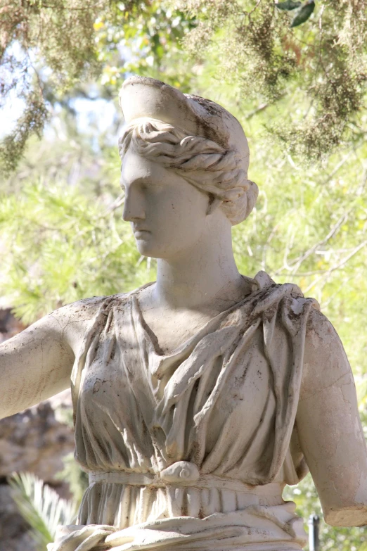 a stone statue standing next to some trees