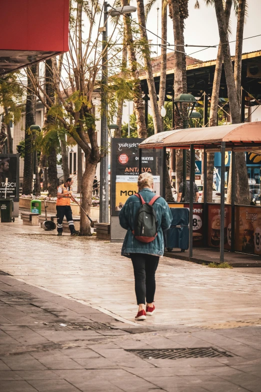 a woman in blue jacket walking down street near people