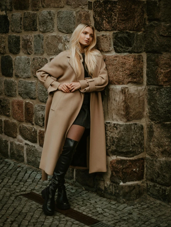 a blonde girl is standing against a brick wall