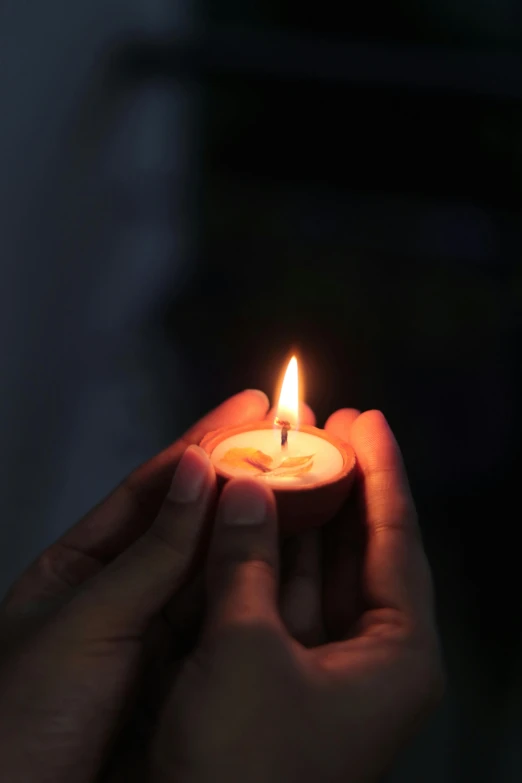 a person holding a small lit candle in their hand