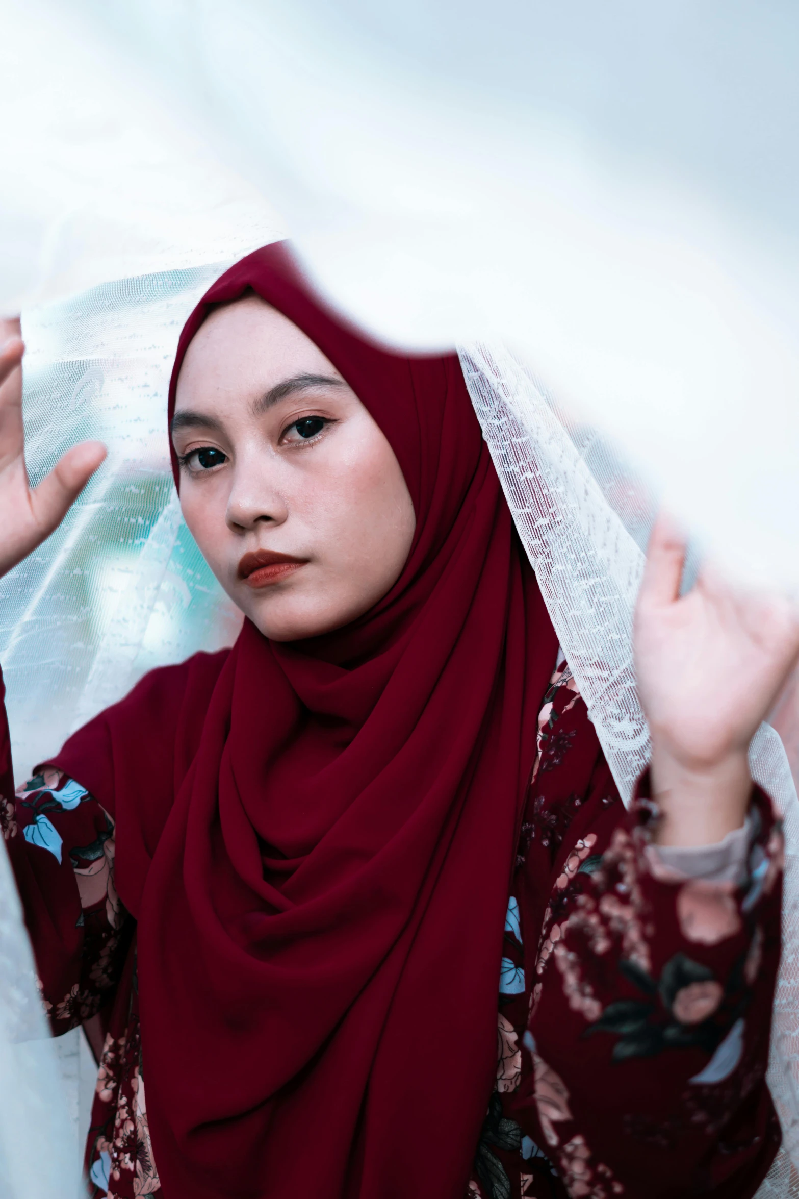 a woman in maroon with a white shawl over her head