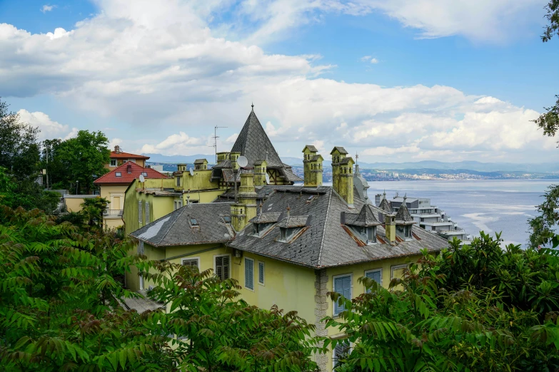 this is the view from an overlook of an old, thatched - roofed house with a lake in the background