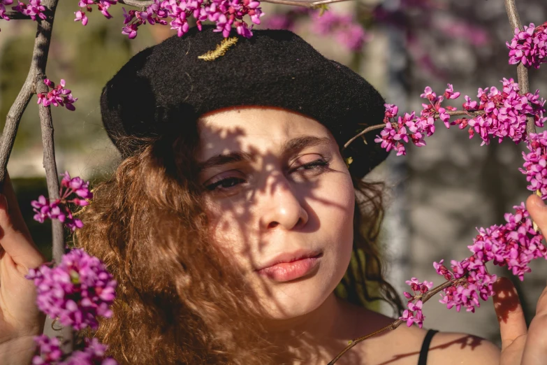 the young woman is posing in front of a pink tree