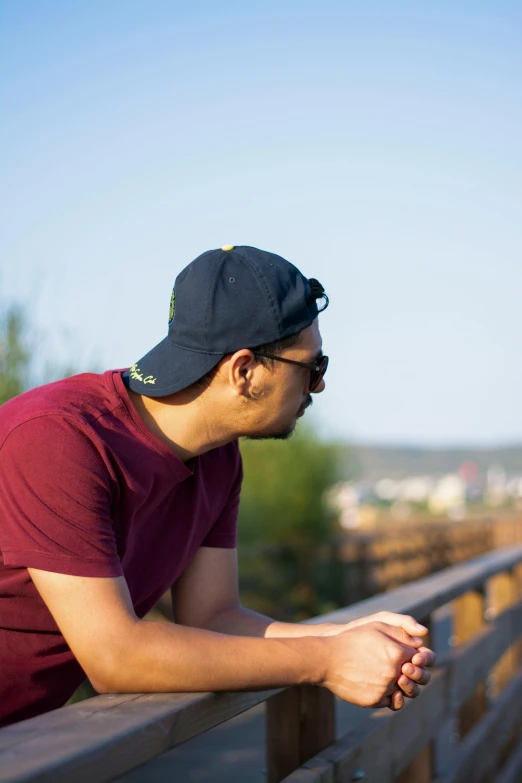 a young man leans against a wooden railing