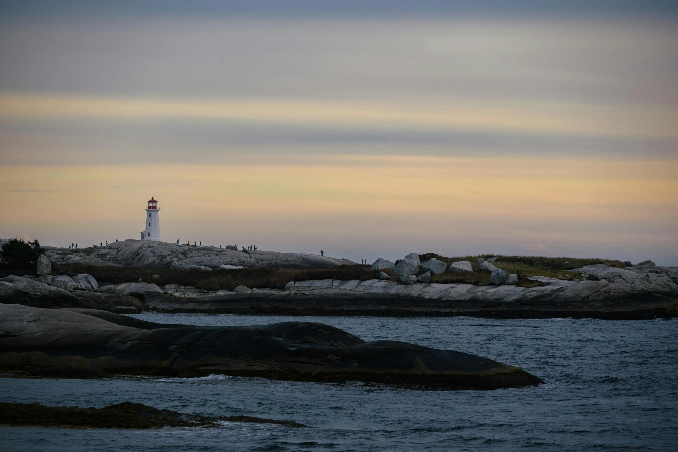 lighthouse on a rock near the ocean at sunset