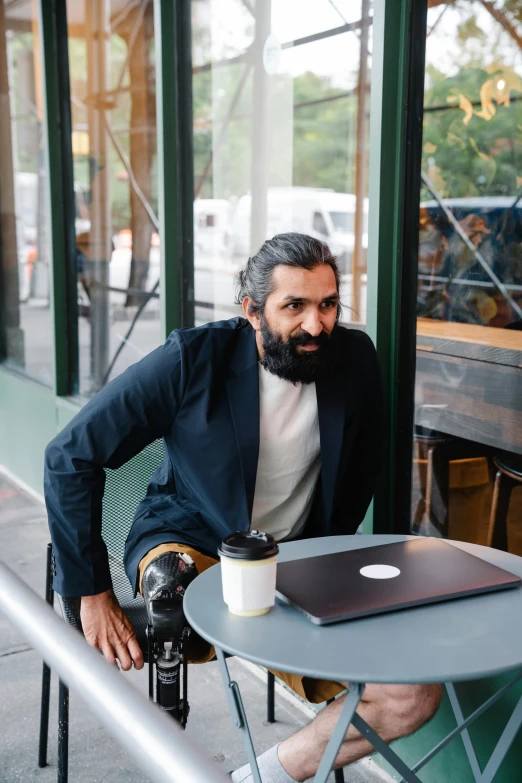 a man in a black blazer sitting at a table