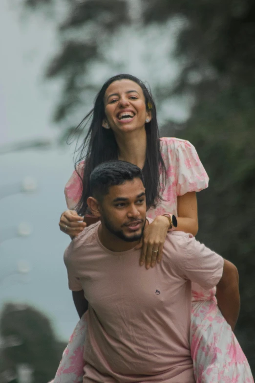 a man on the shoulders of a young woman in a pink dress