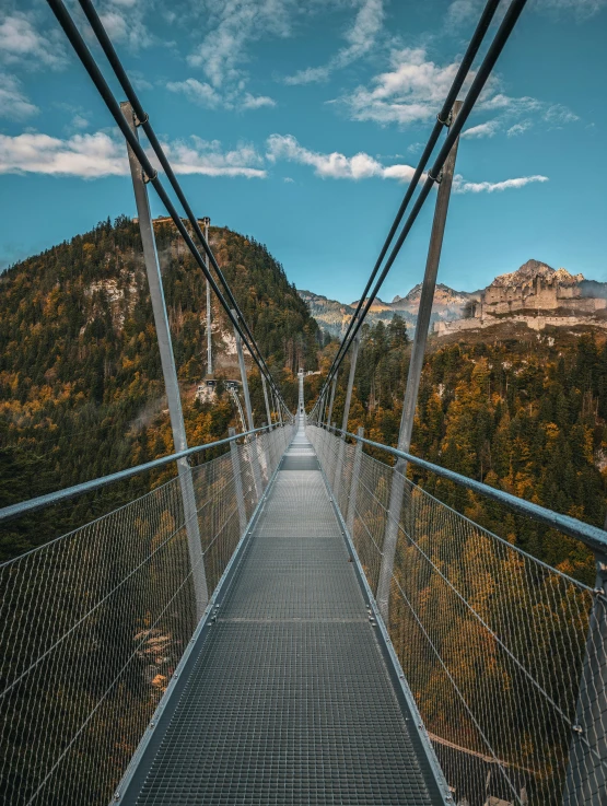 a wooden walkway suspended over a river near mountains