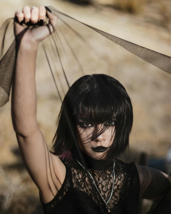 a woman with black paint looks down while she is holding her hair above her head