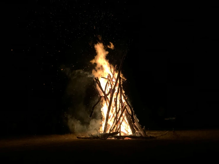 a man standing next to a big bonfire