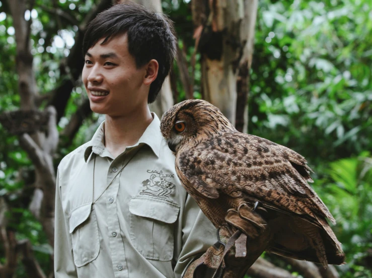 a man is holding up a brown and black owl