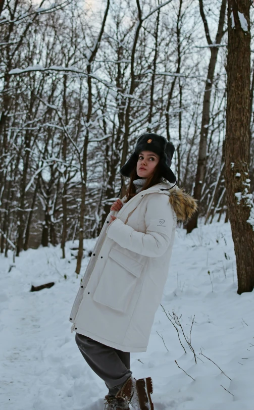 a woman standing outside in the snow and wearing boots