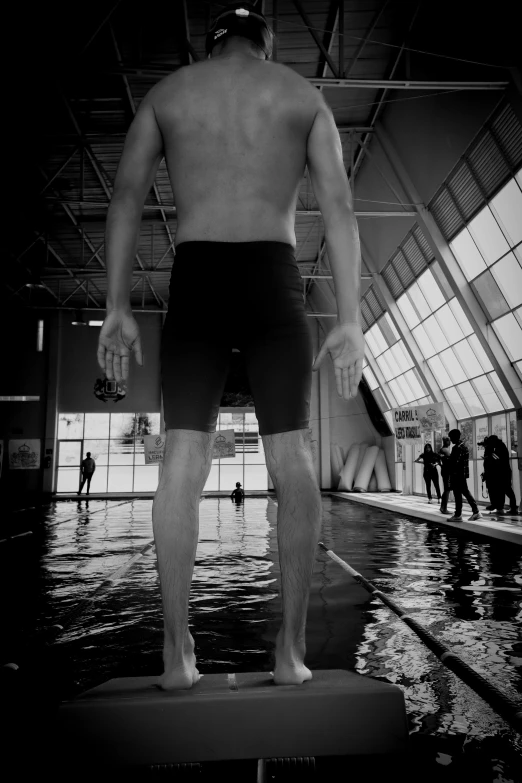 man in swim shorts standing on a platform