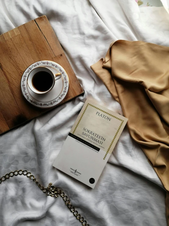 a cup of coffee on a plate next to a book