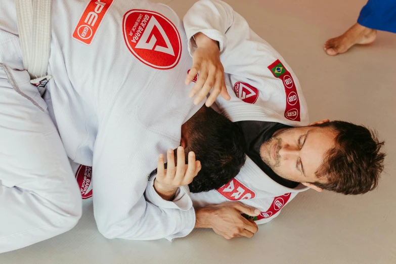 two men wearing red and white uniforms are wrestling with each other