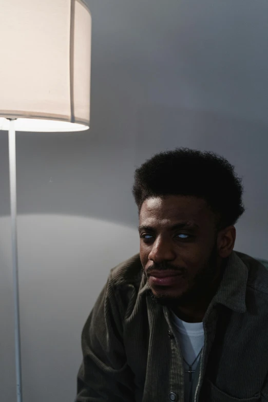 a man sitting under a table lamp in a room