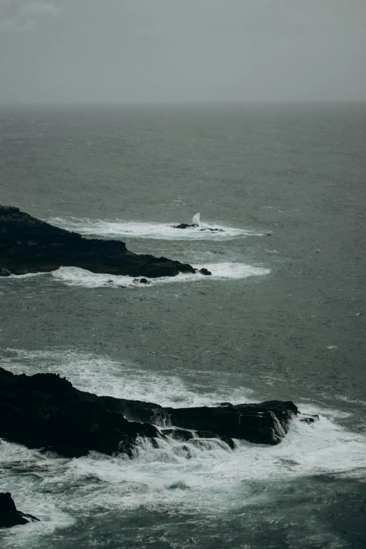 the view of a body of water with two rocks in the middle