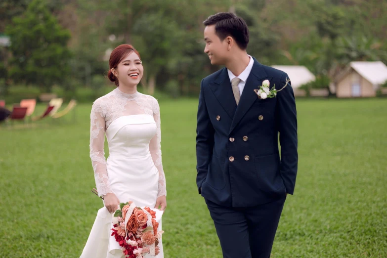 asian couple smiling for camera as bride walks along