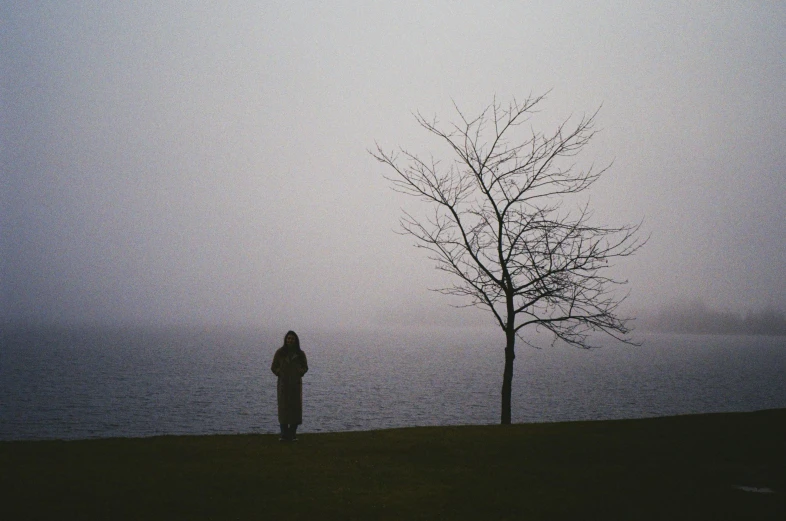 a lone person standing beside the ocean looking at soing on a cloudy day