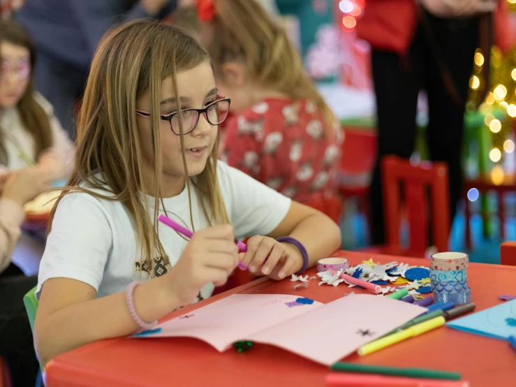 a girl coloring on her book in front of the other students