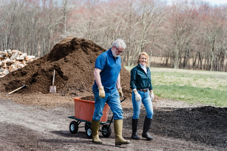 two people with dirt wheels next to a pile of dirt