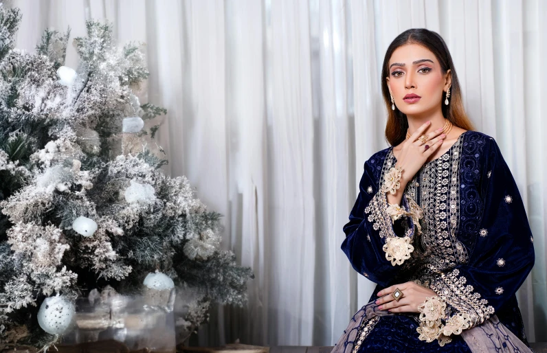 the woman sits on her bed near the christmas tree