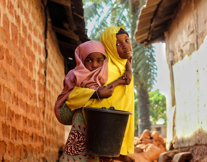 two young women carrying large buckets of food