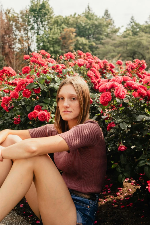 a woman posing for a picture in a flower bed