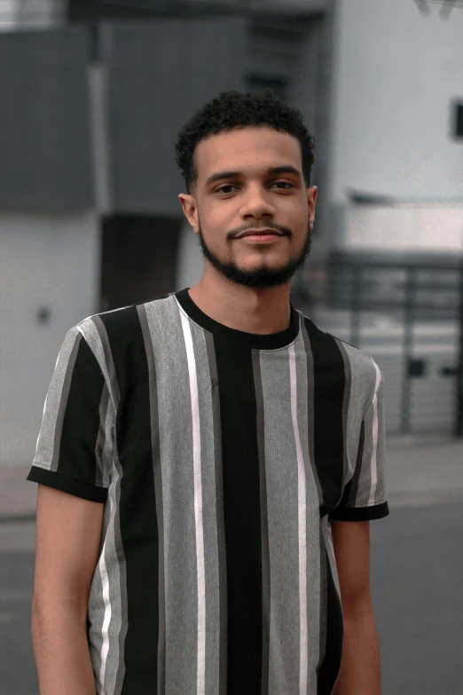 a young man with black hair and beard in a striped shirt