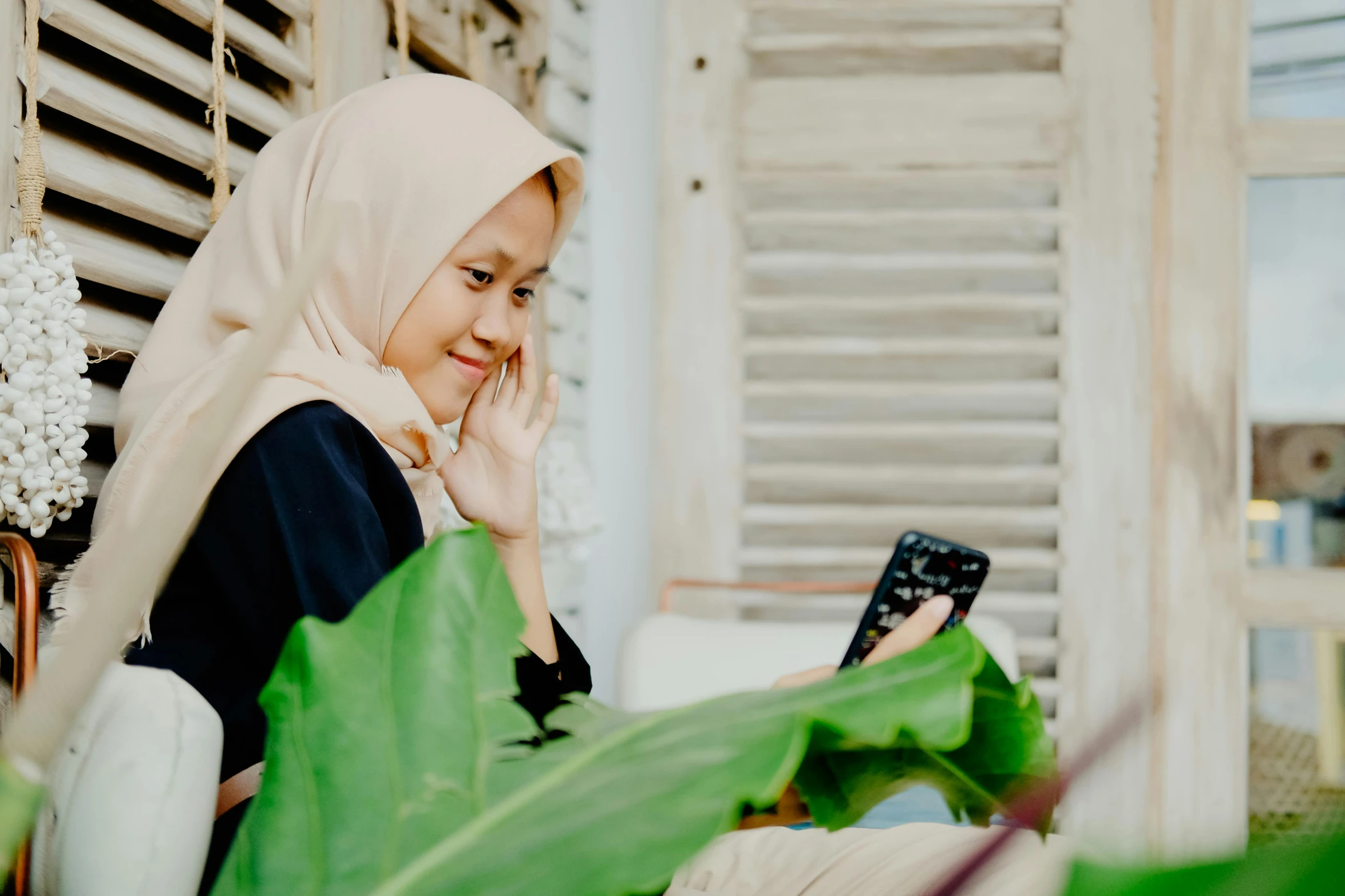 a woman wearing a hijab is looking at her cell phone