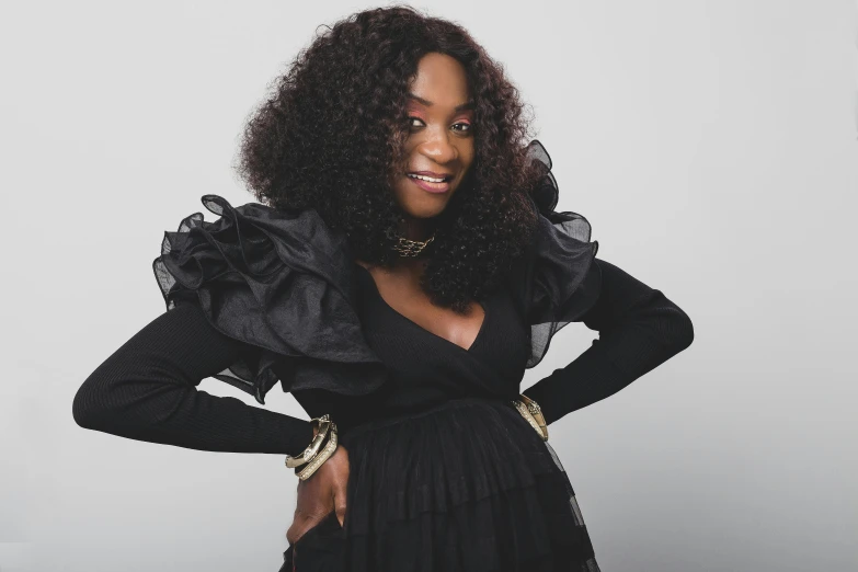 a woman wearing a black dress with ruffled shoulders